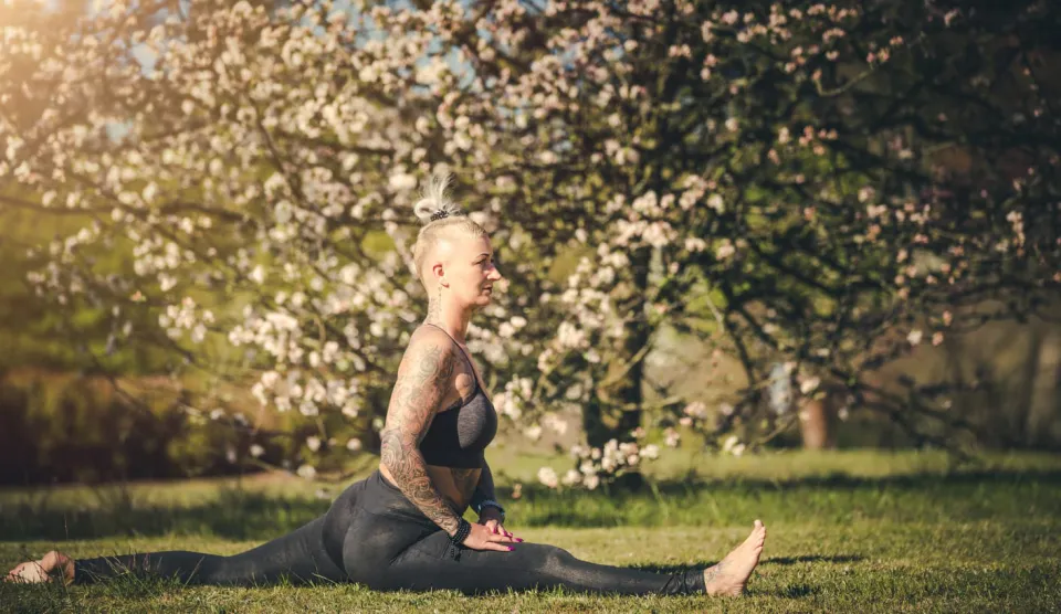 Kati im Seitspagat auf einer Wiese mit Obstblüten