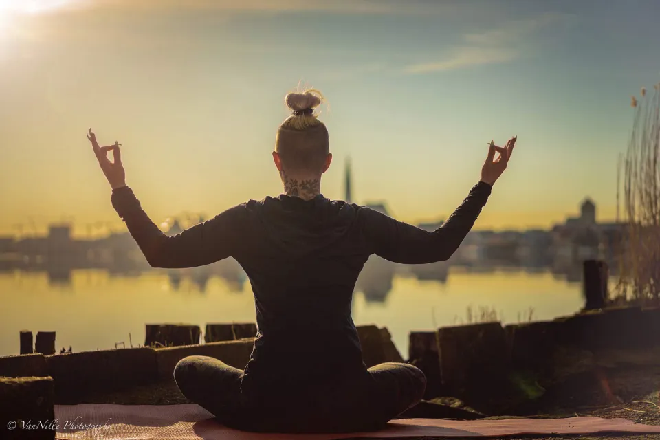 Kati in Meditationshaltung vor der Rostocker Skyline im Abendlicht