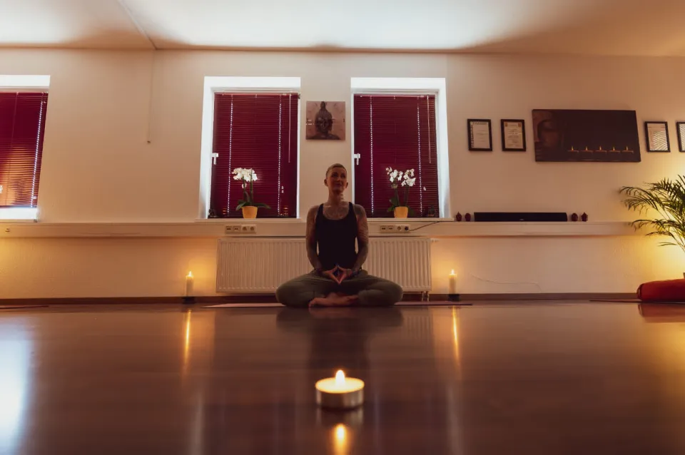 Kati meditiert bei Kerzenlicht im Yogaraum